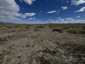 A half circle of stones isolated away from cover or support, on a barren stretch of flat lava rock.