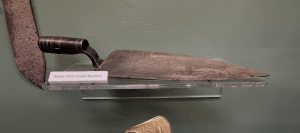 Image of a bayonet the size and shape of a garden trowel. The handle is a cylindrical socket that fits over a rifle's muzzle.